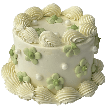  A small mini round shaped Swiss meringue buttercream cake with a white base colour and white piped shells.  Pretty green daisies have been piped on the top and sides of the cake and some sugar pearls added to complete the decoration.