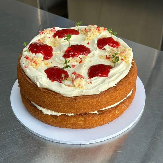 A 2 Layered 8 inch vanilla cake with fresh milk cream, homemade strawberry jam dollops, biscuit crumb & fresh thyme. 