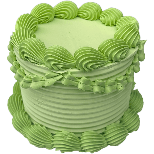 A small round shaped four inch cake coated in a lime green swiss meringue buttercream with large shell piping around the bottom and top of the cake. The side of the cake has textured combed stripes circling it. The top centre of the cake is coated flat and smooth allowing for a message to be written.