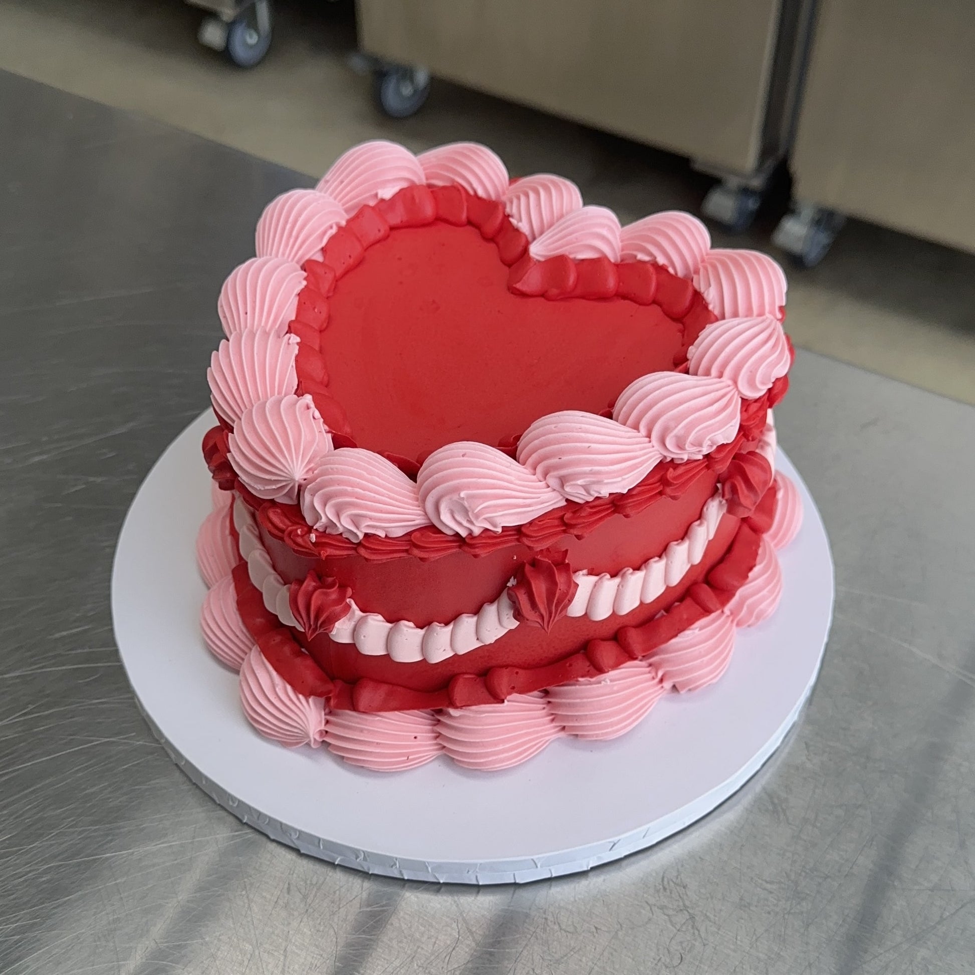 A classically decorated Vintage cake in two tone red and pink buttercream piping.